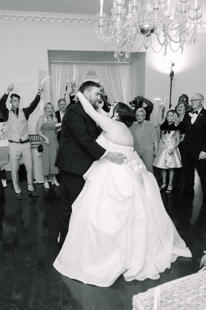 Luxmore Grande Estate | Jennifer Holly Light and Airy Wedding Photographer in Orlando | Bride and groom dance joyfully under a chandelier, surrounded by guests capturing the moment with sparklers. The scene is festive and celebratory.