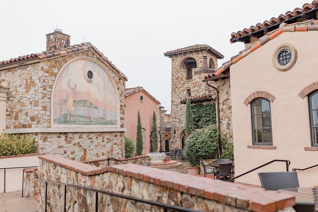 Wedding Venues in Central Florida | Jennifer Holly Light and Airy Wedding Photographer in Orlando | Rustic stone buildings with terracotta roofs form a courtyard. Tall cypress trees and ivy add greenery. The scene evokes a serene, Mediterranean vibe.