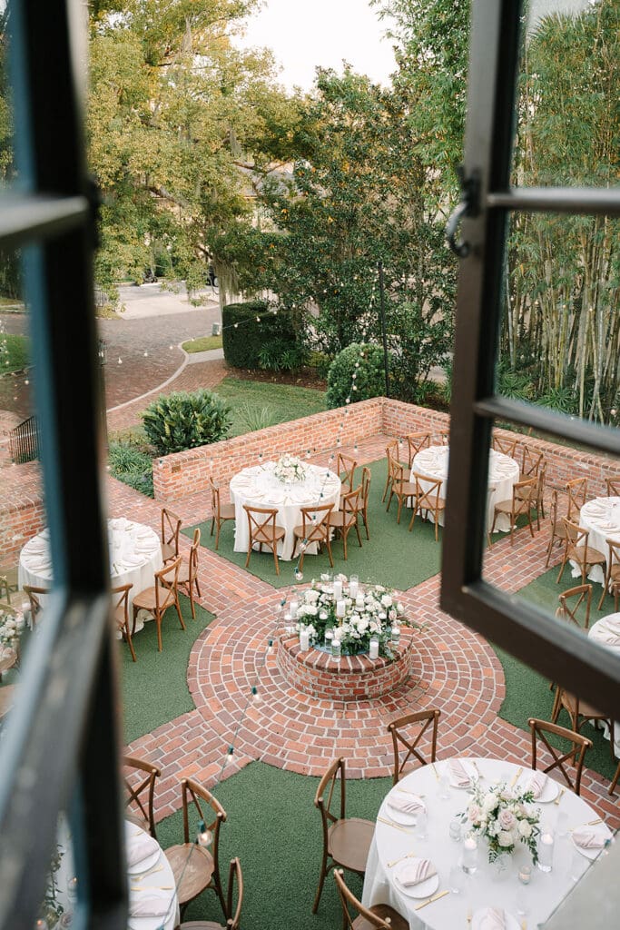 Casa Feliz Wedding | Jennifer Holly Light and Airy Wedding Photographer in Orlando | Outdoor courtyard with round tables set for an event. Brick pathways, lush greenery, and elegant centerpieces create a serene, inviting atmosphere.