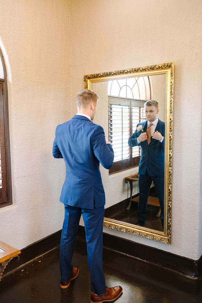 groom in a blue suit getting dressed at The Howey Mansion captured by Jennifer Holly Photography