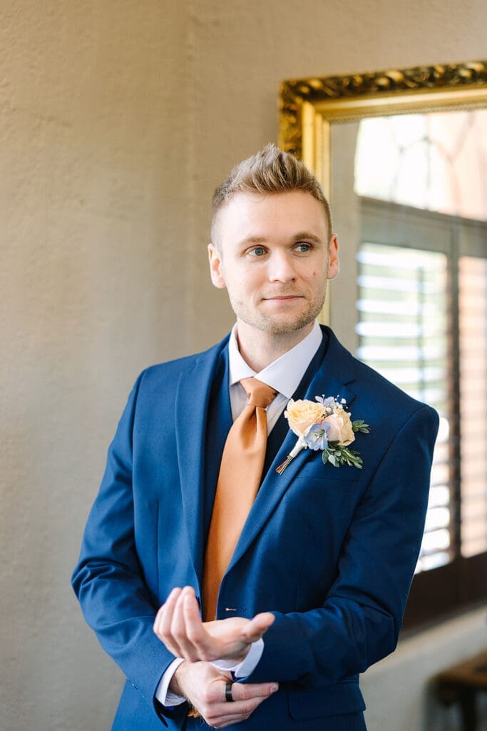 groom in a blue suit getting dressed at The Howey Mansion captured by Jennifer Holly Photography