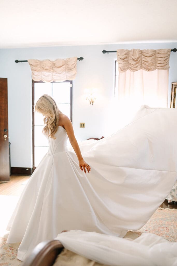 bride in a white strapless gown with the train being lifted behind her at a wedding at The Howey Mansion captured by Jennifer Holly Photography