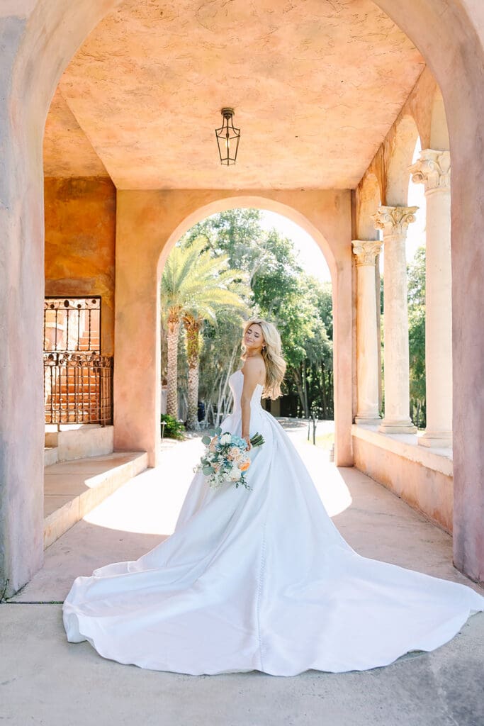 bride portrait under stone archway holding bouquet at The Howey Mansion captured by Jennifer Holly Photography