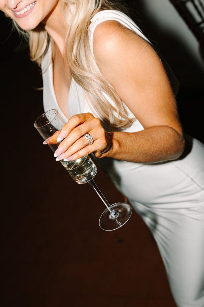 bride holding a glass of champagne showing off her ring at The Howey Mansion captured by Jennifer Holly Photography