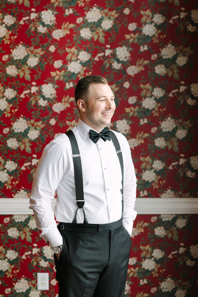 groom portrait in front of red floral wallpaper at Florida mansion wedding venue, Luxmore Grande Estate, captured by Jennifer Holly Photography