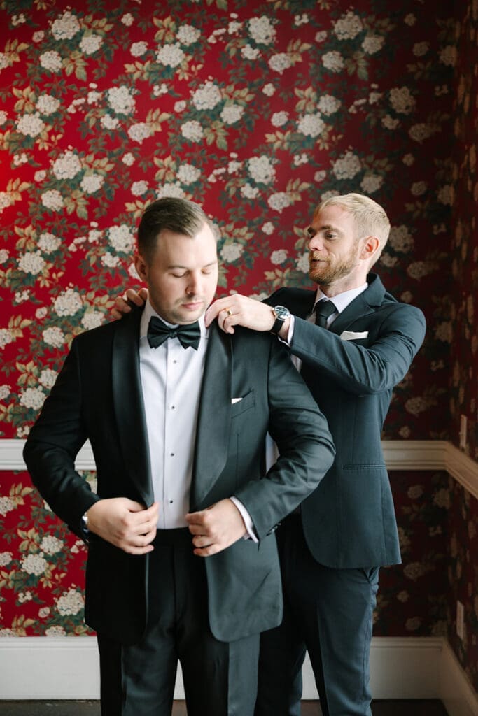 groom portrait in front of red floral wallpaper at Florida mansion wedding venue, Luxmore Grande Estate, captured by Jennifer Holly Photography