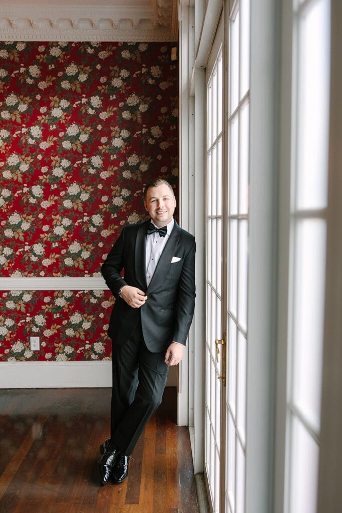 groom portrait in front of red floral wallpaper at Florida mansion wedding venue, Luxmore Grande Estate, captured by Jennifer Holly Photography