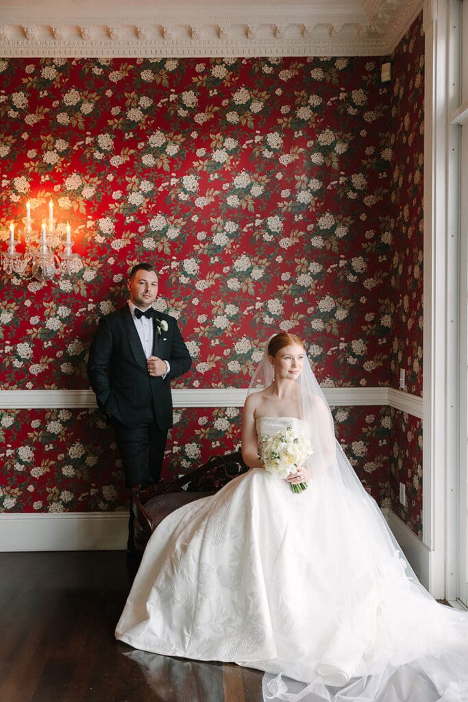 bride and groom portrait in front of red floral wallpaper at Florida mansion wedding venue, Luxmore Grande Estate, captured by Jennifer Holly Photography