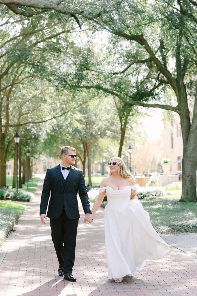 bride and groom walking down a brick path with sunglasses on at Rollins College, captured by Florida elopement photographer Jennifer Holly Photography