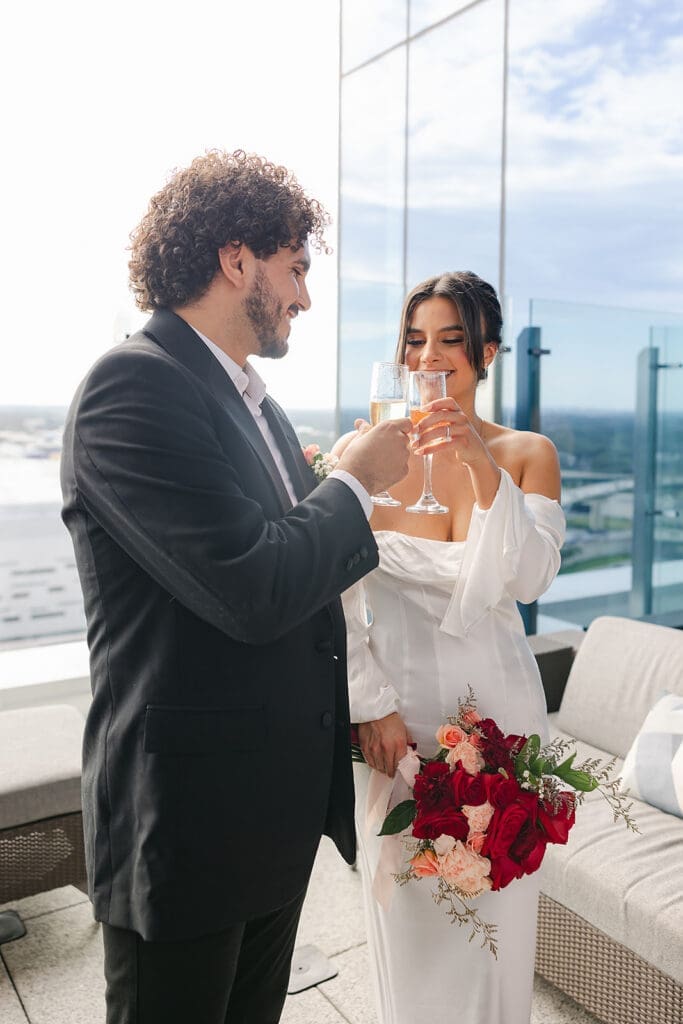 bride and groom cheers champagne glasses in downtown Orlando in an elopement portrait captured by Jennifer Holly Photography, an Orlando elopement and wedding photographer