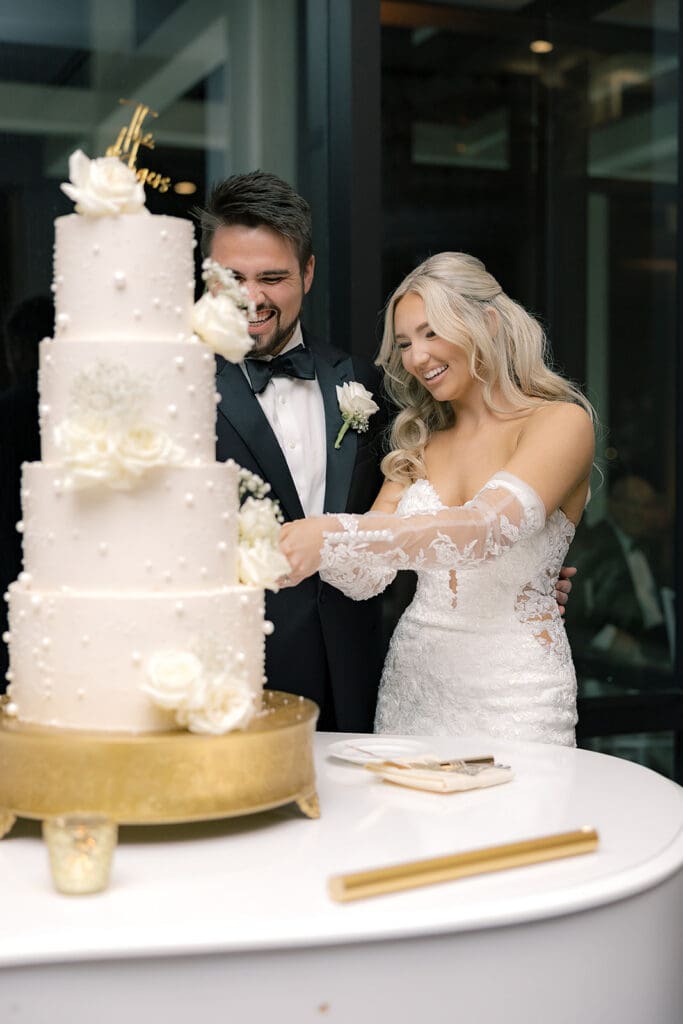 bride and groom cutting a four-tiered white wedding cake on a grand piano at a wedding reception at Hyatt Regency Grand Cypress Resort in Orlando, Florida, captured by Jennifer Holly Photography