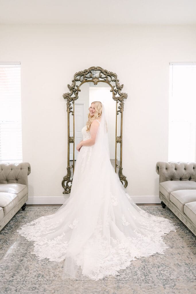 bride standing in front of an embellished mirror in her wedding gown at Sterling Event Venue in Minneola FL captured by Jennifer Holly Photography